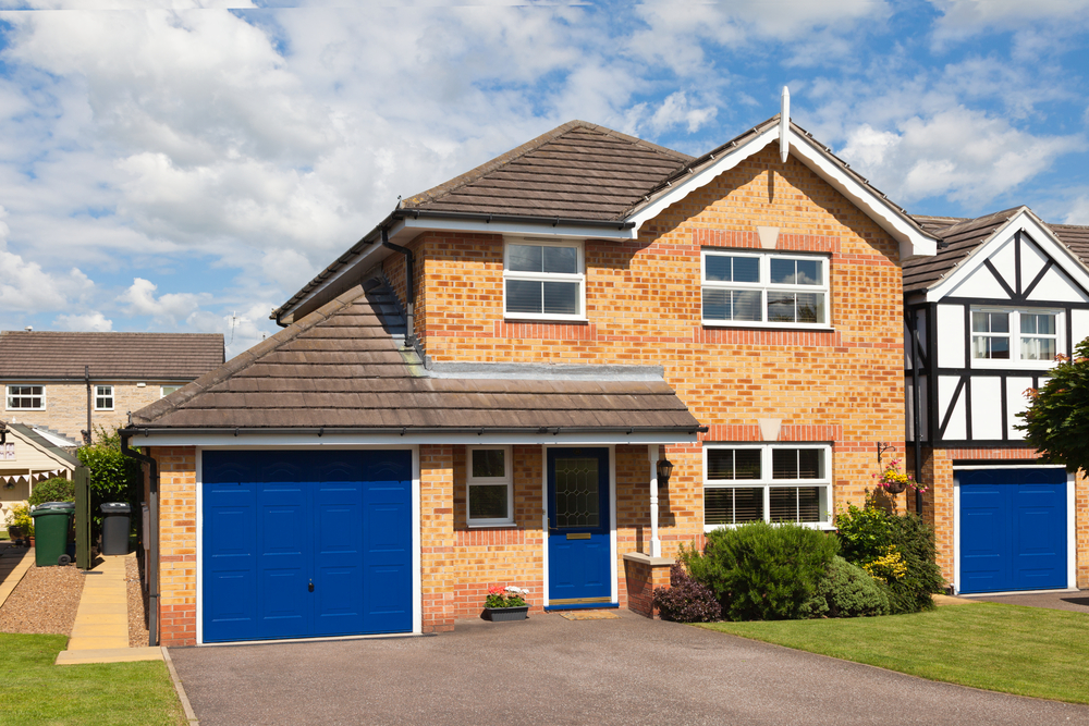 Bright blue steel garage doors installed on a brick house.